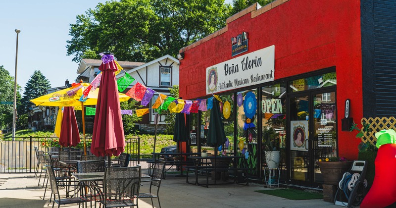 Exterior, restaurant front, seating area, tables with chairs, parasols, metal railing
