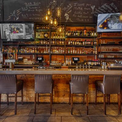 Bar area featuring stocked shelves, chalkboard with bar rules, and soft lights.