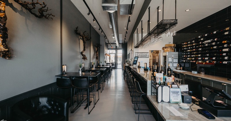 A modern wine bar - a gray walls, artistic branch sculptures, high-top tables, a marble bar counter