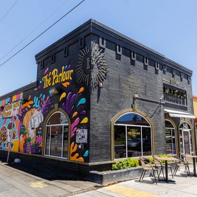 Restaurant's building featuring dark-brick exterior adorned with a large, colorful mural.