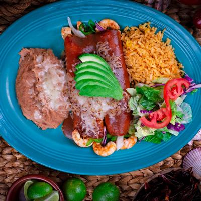 Enchiladas smothered in red salsa and cheese sauce, with shrimp, rice, beans, and salad.