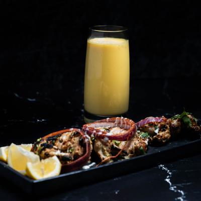 Chicken tikka served with lemon wedges, accompanied with mango lassi.