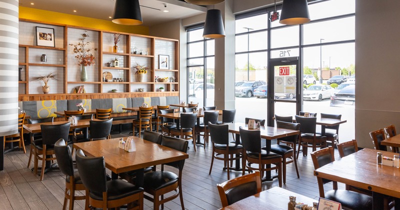 Modern cafe interior with wooden tables and chairs, large windows