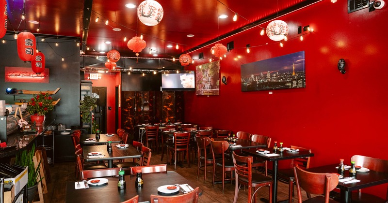 Interior of a restaurant with red walls, wooden tables set for dining, and decorative lanterns