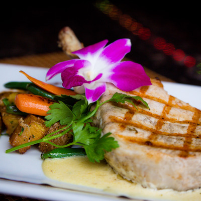 Pork chop with potatoes, carrots, green beans, and an edible orchid.