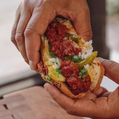 Hands holding a Chili Hot Dog.