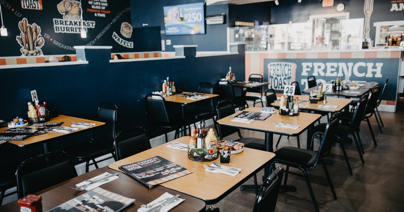 Interior of a modern diner-style restaurant with wooden tables and black chairs