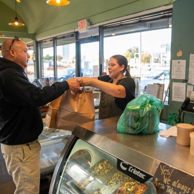 An employee handing an order to a guest at a counter.