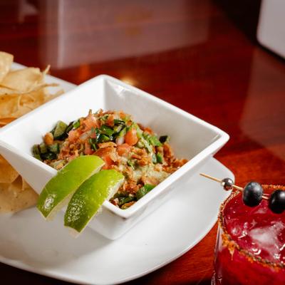 Fresh guacamole served with tortilla chips and lime wedges.