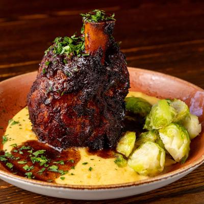 Osso Bucco served with polenta and brussels sprouts.