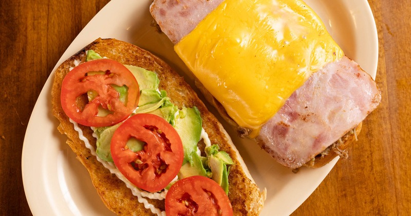 Ham and cheese sandwich topped with sliced avocado and tomato