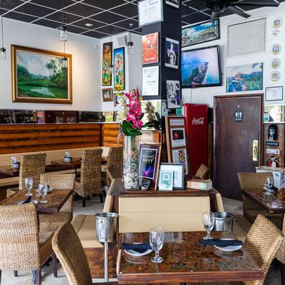 Interior with walls covered in art, wicker chairs, and set tables.