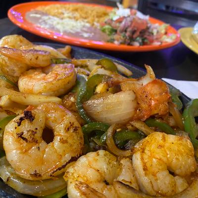 Close-up of shrimp fajitas, other dish in the background.