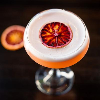 An orange cocktail drink with citrus wheel garnish, top view.