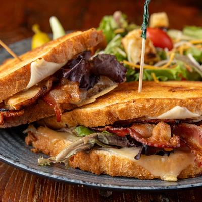Turkey Club sandwich with bacon and cranberry relish, served with salad.
