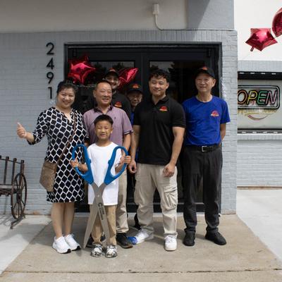 Group of people posing with giant scissors.