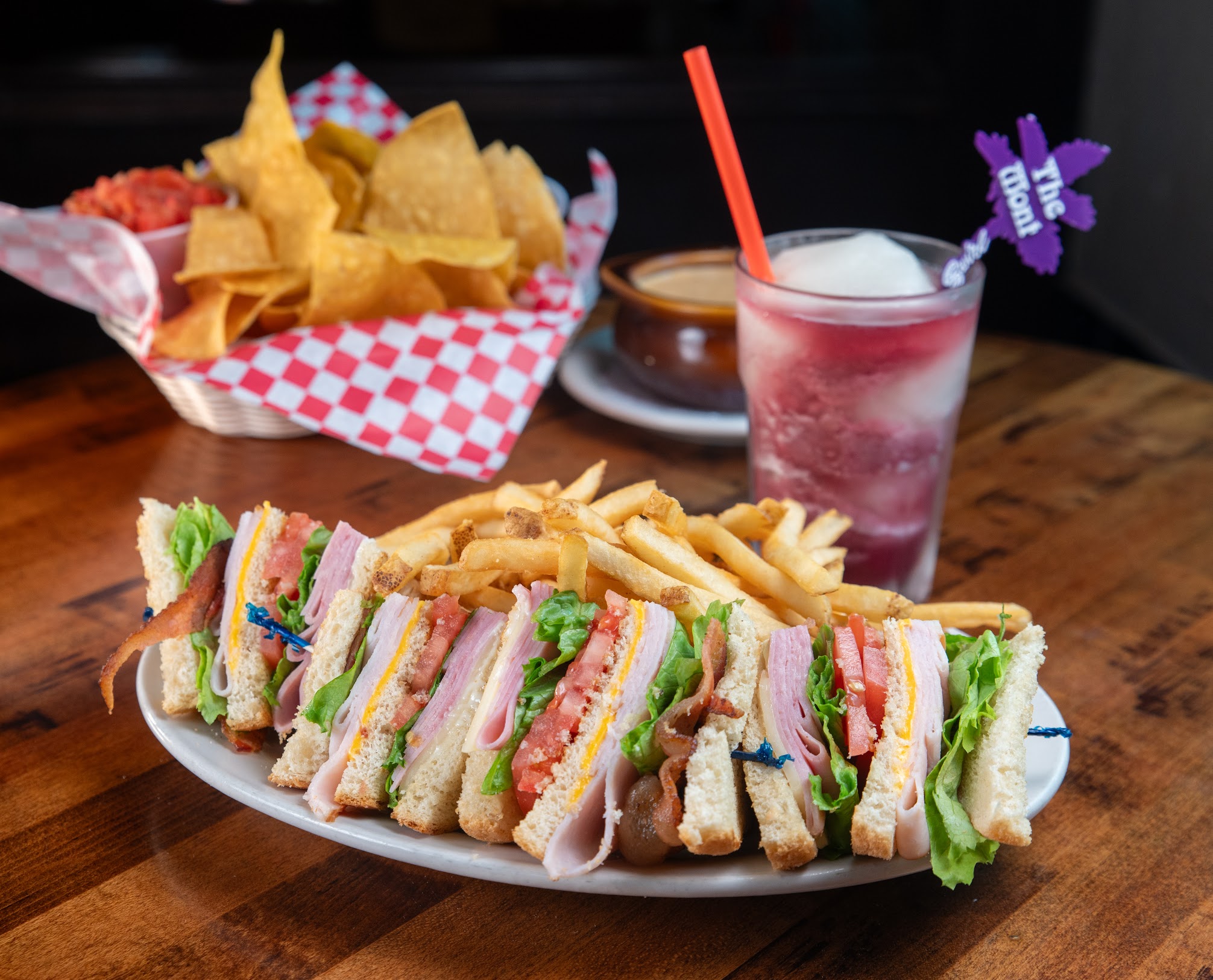 Club sandwiches served with fries, tortilla chips, and a frozen cocktail