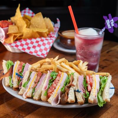 Club sandwiches served with fries, tortilla chips, and a frozen cocktail.