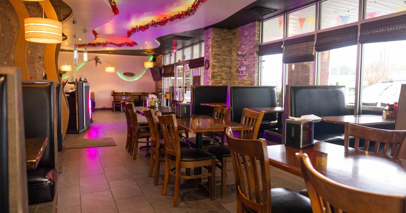 A restaurant interior with wooden tables and chairs, and black leather booths