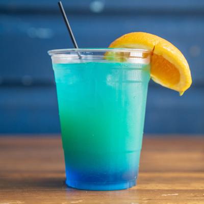 A cup of blue cocktail garnished with an orange wedge.