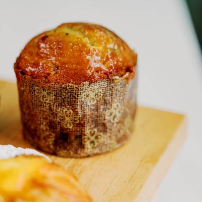 A golden-brown muffin with a decorative liner on a wooden surface, close up.