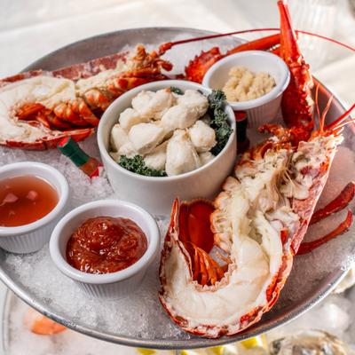 Seafood platter with lobster, crab claws and sauces on ice..