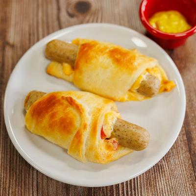 Two cheesy sausage rolls on a white plate.