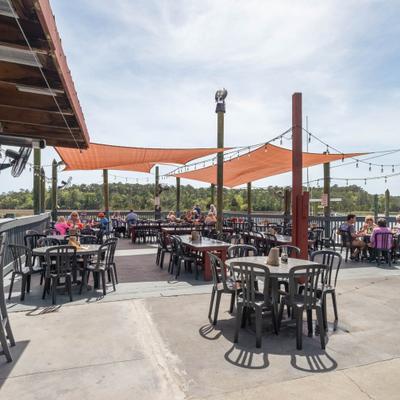 Outdoor patio seating area with tables and shade sails.