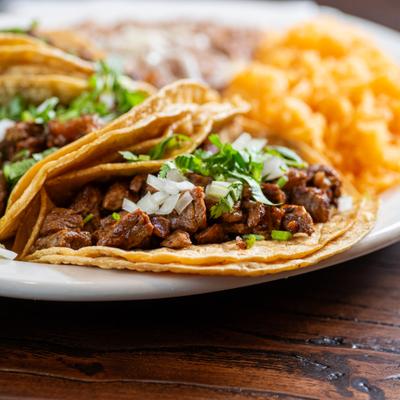 Close-up of a Mexican street-style taco with chopped parsley and onions.