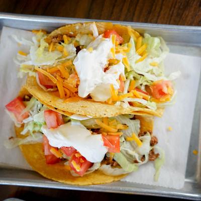 Tacos, topped with lettuce, tomato, cheese and sour cream