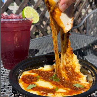 Hand stretching cheese from Queso Flameado dish.