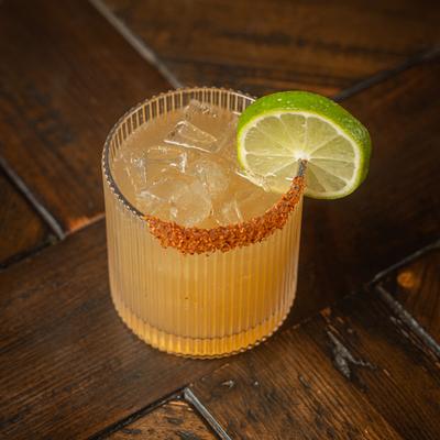 Spicy Margarita garnished with a lime wheel on a wooden table.