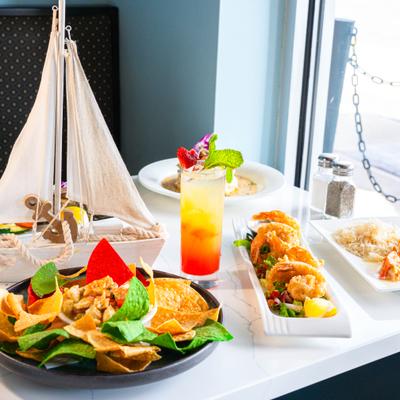 Colorful seafood meal served with a cocktail on a table near a window.
