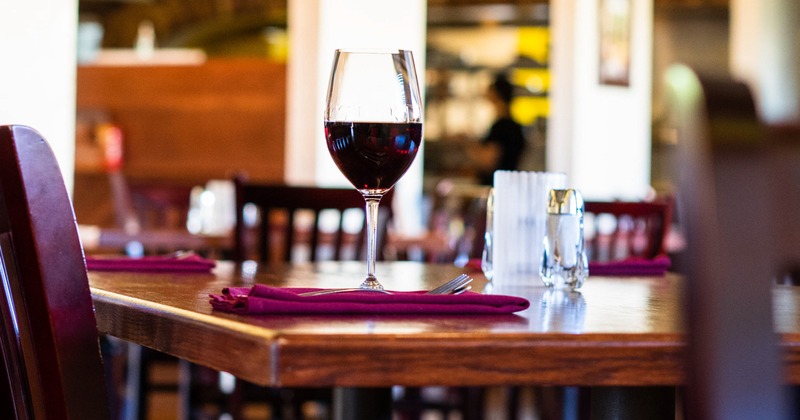 Inside, a glass of red wine served on a red napkin with cutlery, table closeup