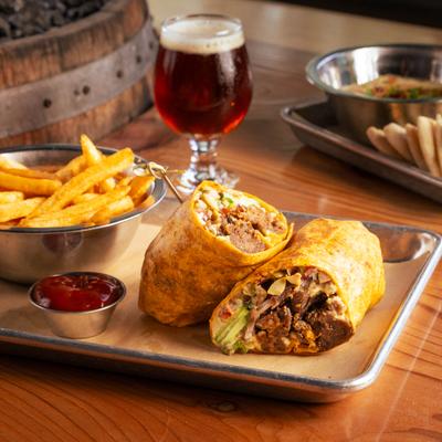 Vegan shiitake mushroom wrap served with fries, ketchup, and a glass of beer.