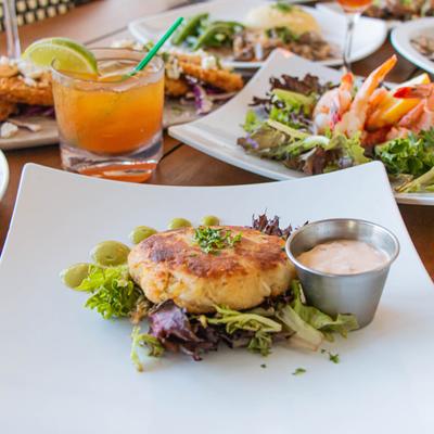 Blue crab cake served with lemon butter, on a table with assorted food plates.
