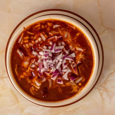 Bowl of chili topped with chopped onions.