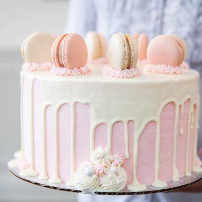 Ombre style vanilla cake with strawberry and vanilla macarons on top.