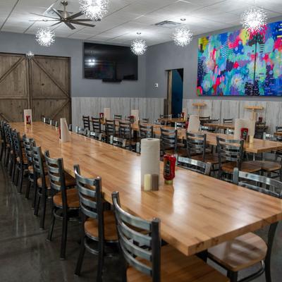 Dining room with wooden tables, metal chairs, and a colorful abstract painting on a wall.