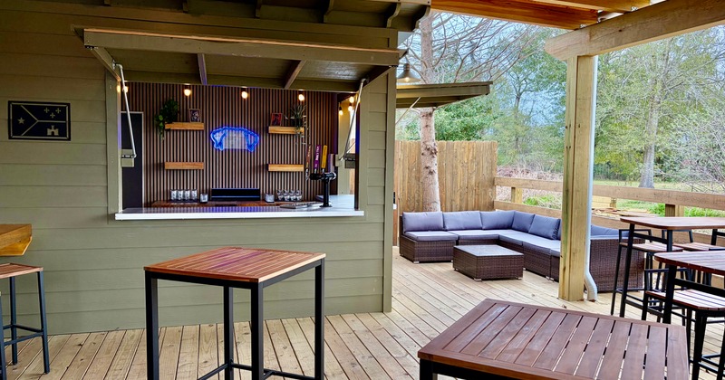 Outdoor bar area with wooden tables and a cushioned corner seating sofa