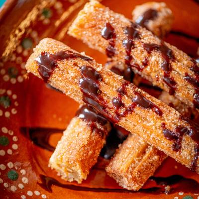 Four churros drizzled with chocolate sauce.