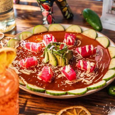 Spicy red sauce with raw tuna, fresh cucumbers, and centered avocado rose.