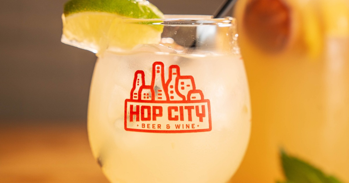 Margarita cocktail served in a branded glass with a lime wedge garnish
