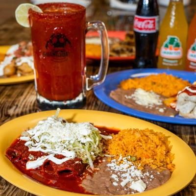 Enchiladas topped with red sauce, lettuce, and cheese, served with rice and beans.