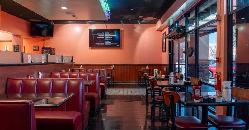 Interior - red booths, wooden tables and chairs, a wall-mounted TV and large glass windows