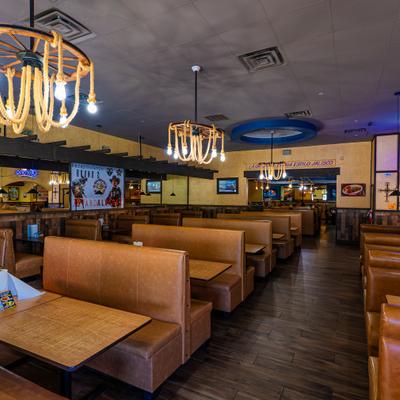 Dining area  furnished with brown leather booths and wooden tables.