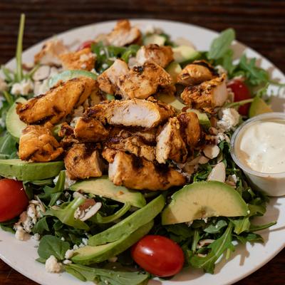 Grilled chicken salad with a creamy white dressing cup.