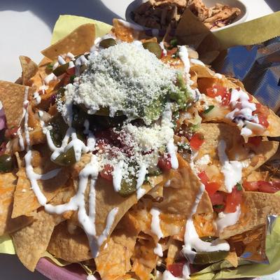Nachos topped with cheese, guacamole, sour cream and salsa