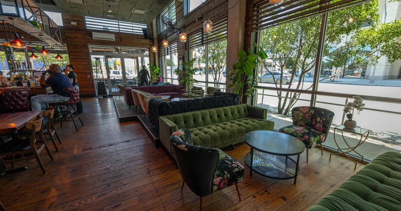 Interior, wooden floors, green sofas, floral chairs, and large windows