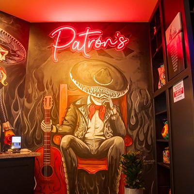 Mural of a skeleton in a mariachi outfit, holding a guitar, red neon sign above reads Patron's.